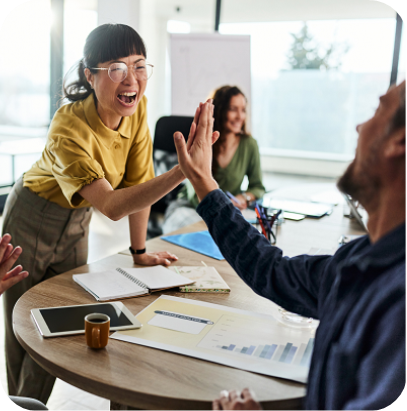 Cheerful Japanese businesswoman giving high-five to her male colleague during a casual meeting in the office.