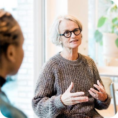 Senior woman talking with participants in a group therapy session