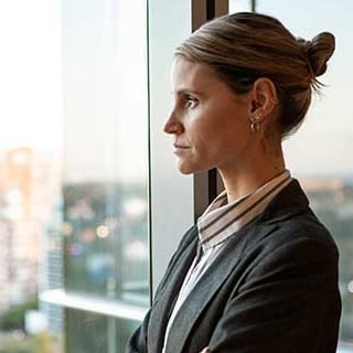 Side view of a confident businesswoman looking thoughtfully out of a window during the daytime.