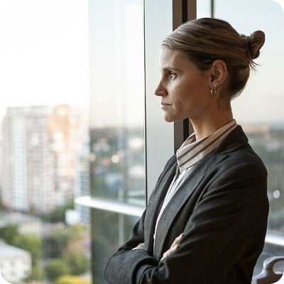 Side view of a confident businesswoman looking thoughtfully out of a window during the daytime.