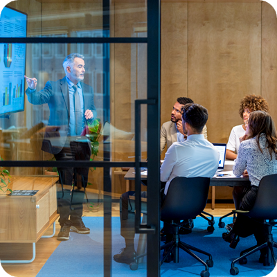 Mature man giving a big data presentation on a tv in a board room