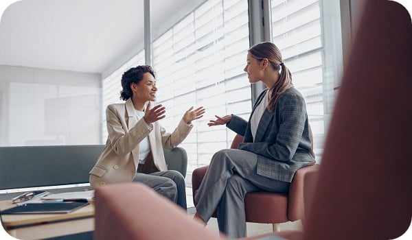 Smiling young female colleagues brainstorming and sharing ideas at the workplace