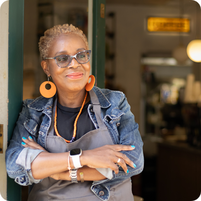 Happy looking cafe owner standing in doorway with arms folded