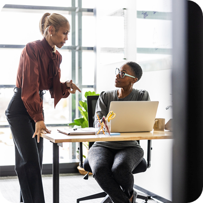 Female colleagues working on laptop in modern office space