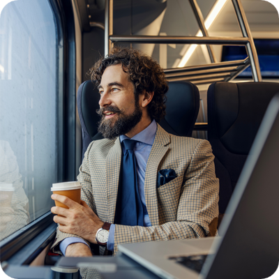 Businessman commuting by train enjoying coffee looking out window