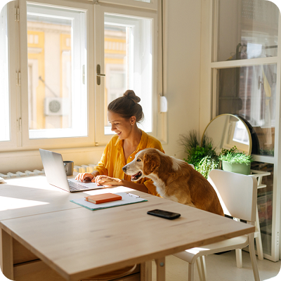 Photo of a young woman who is working from her home office together with her dog.