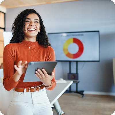 Smiling businesswoman with curly hair presents data on a tablet. 