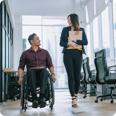 Indian white collar male worker in wheelchair having cheerful discussion conversation with his female asain chinese colleague coworking at walkway corridor