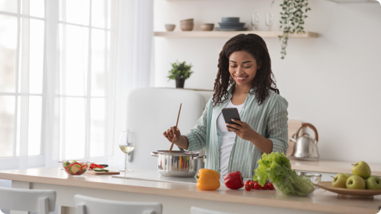 Woman cooking in a kitchen while using a smartphone