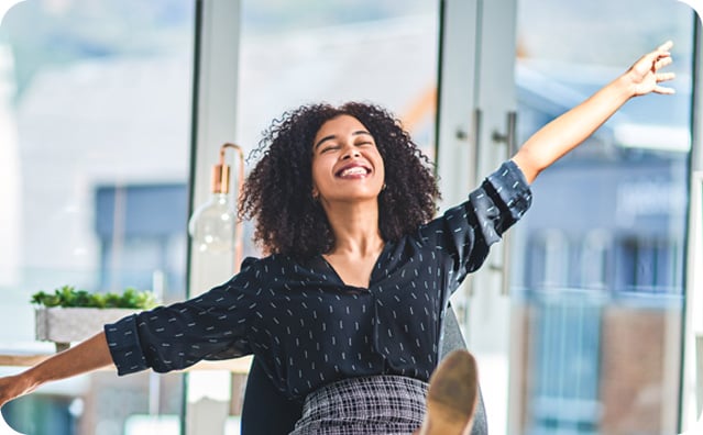 Woman smiling with arms outstretched in bright office