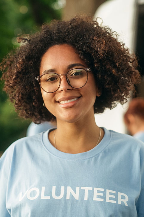 Image of a woman in glasses and a volunteer shirt, symbolizing responsibility in insurance.