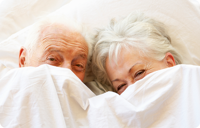 Senior couple hiding under bedsheets