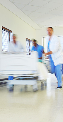 Cirujanos corren con la cama de un paciente en el pasillo de un hospital.