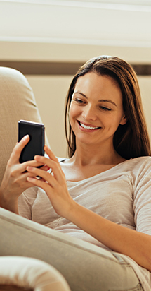 Mujeres jóvenes sonriendo contentas mirando a su teléfono móvil.