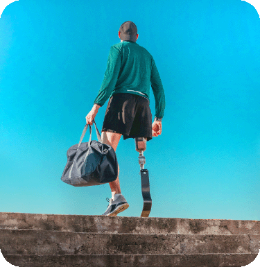 homme de dos avec une prothèse de jambe montant des marches